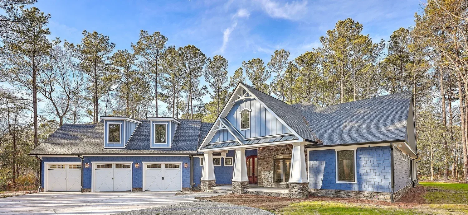 Custom board-and-batten home with a three-car garage and stone columns built by Hale Development, set among Lowcountry pines